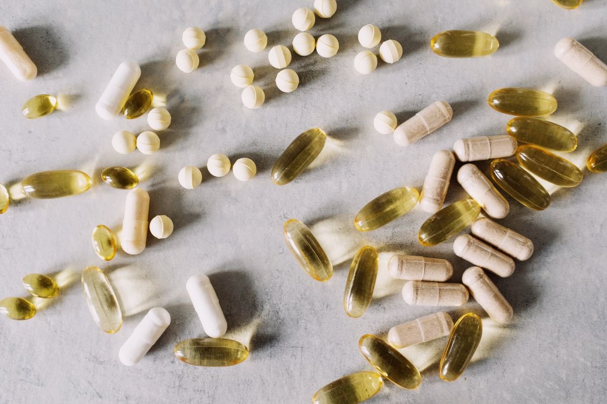 Assorted supplement capsules and soft gels scattered on a grey surface