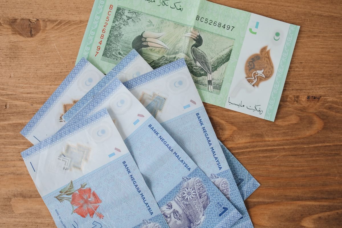 Malaysian ringgit banknotes in several denominations, including RM1 and RM5 notes, spread on a wooden table